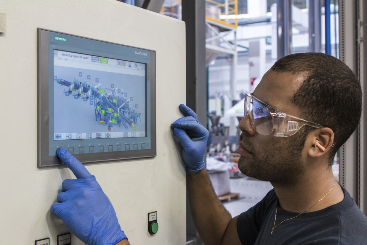 Manufacturing professional using a touch screen to interface with factory equipment